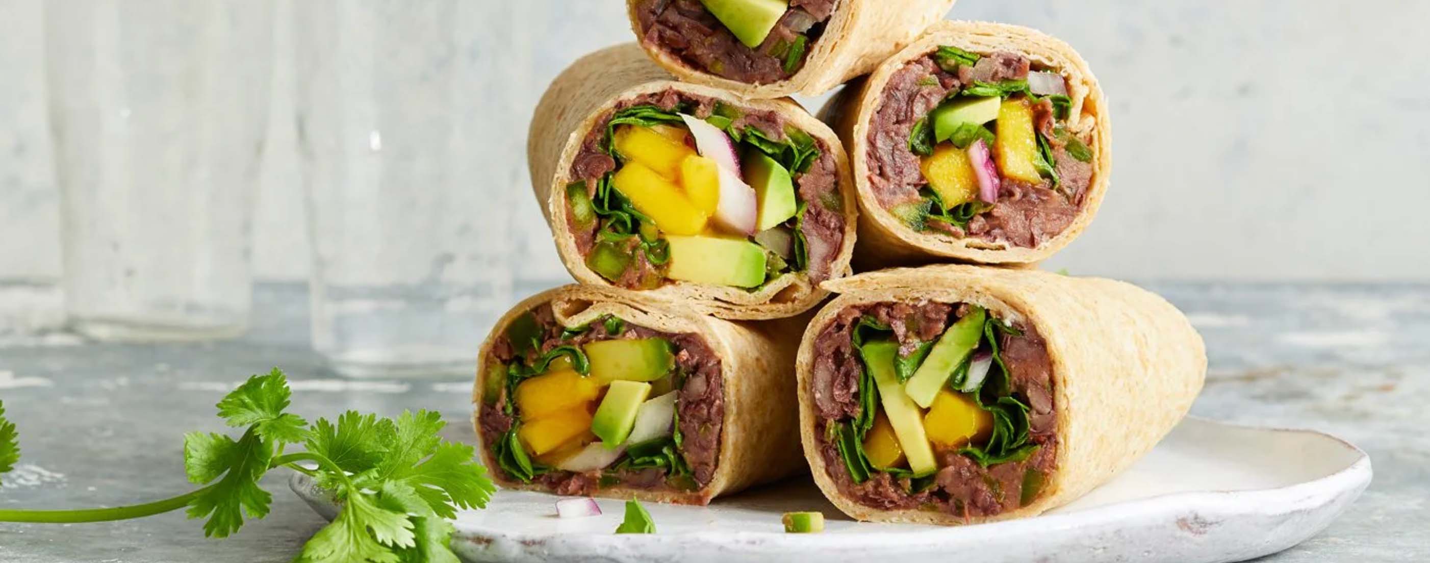 Colorful black bean and avocado wrap cut in half showing the vibrant filling inside